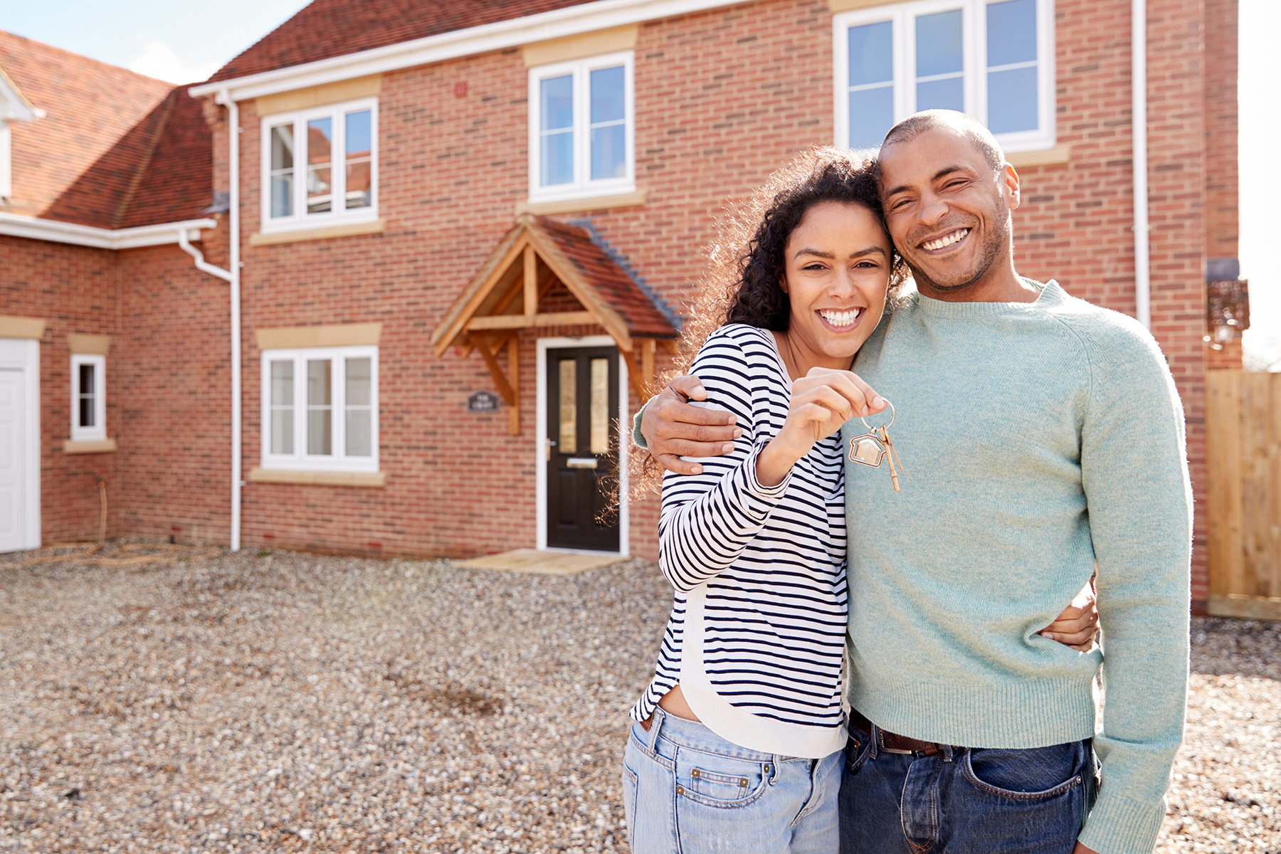 Portrait Of Couple Holding Keys Standing Outside New Home On Moving Day