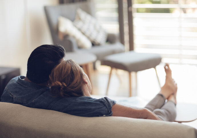 High angle shot of an unrecognizable couple relaxing on their couch at home