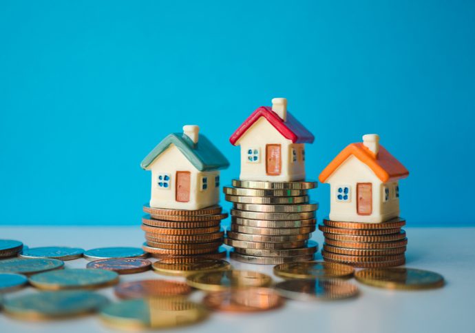 Miniature colorful house with stack coins on blue background using as property and financial concept