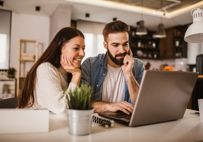 Happy couple enjoying work from home. Happy couple doing business together working at home on the laptop.