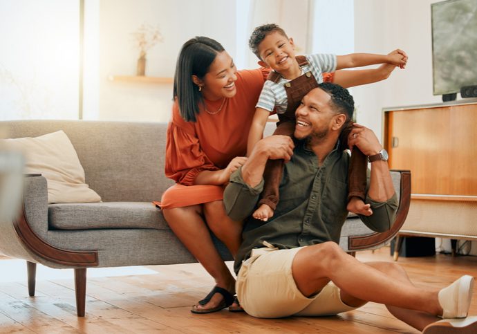 A happy mixed race family of three relaxing in the lounge and being playful together. Loving black family bonding with their son while playing fun games on the sofa at home