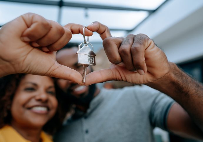 Couple second key to new home with hand in heart symbol