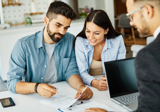 Real estate agent with couple closing a deal and signing a contract