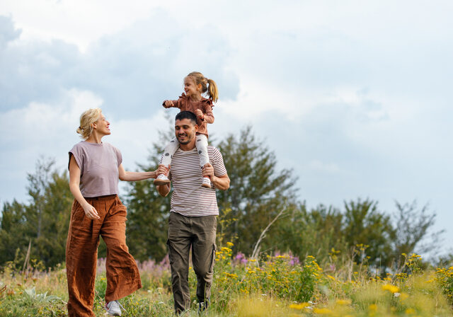 A joyful family enjoying a walk in the countryside, surrounded by lush greenery and wildflowers, embodying happiness and togetherness in nature.